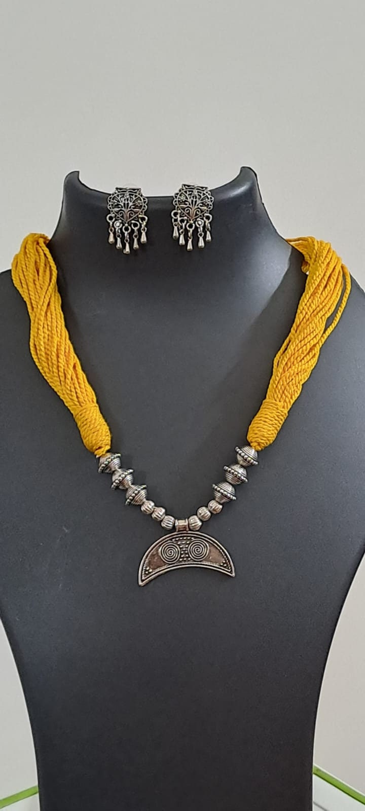 Yellow thread necklace with oxidised silver dokra pendant