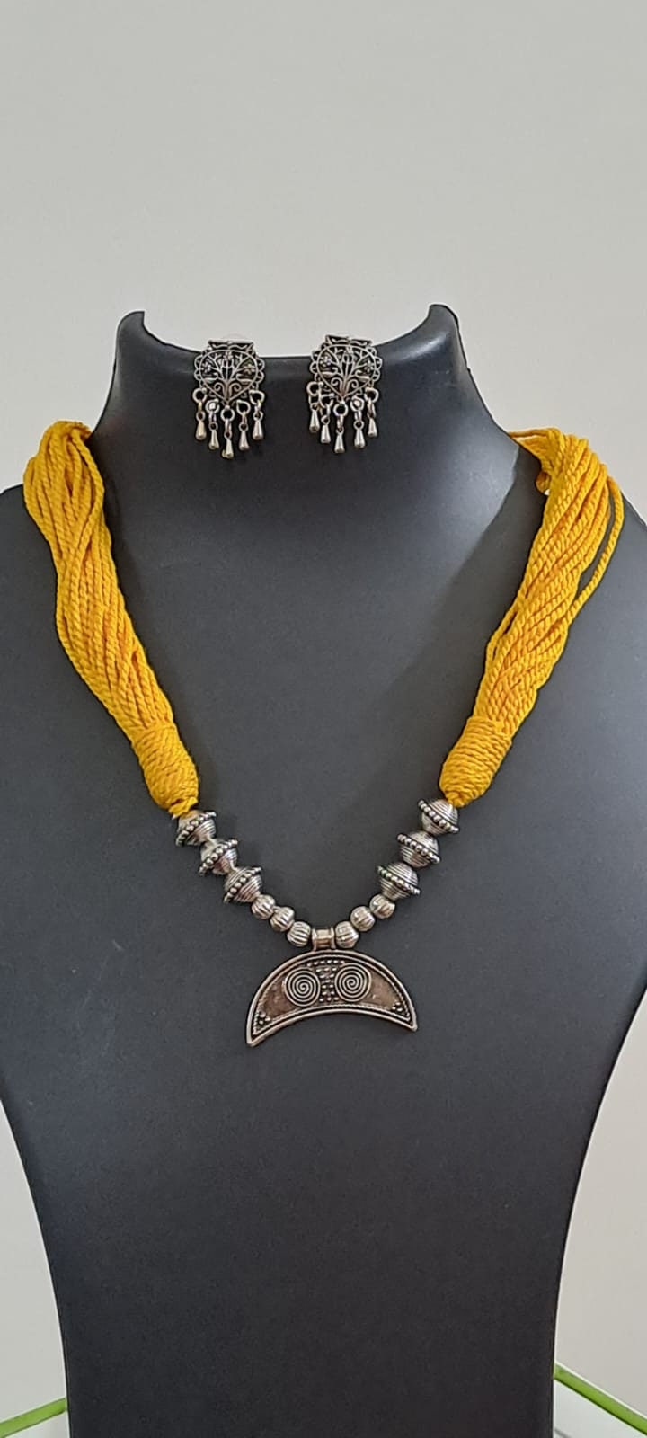 Yellow thread necklace with oxidised silver dokra pendant