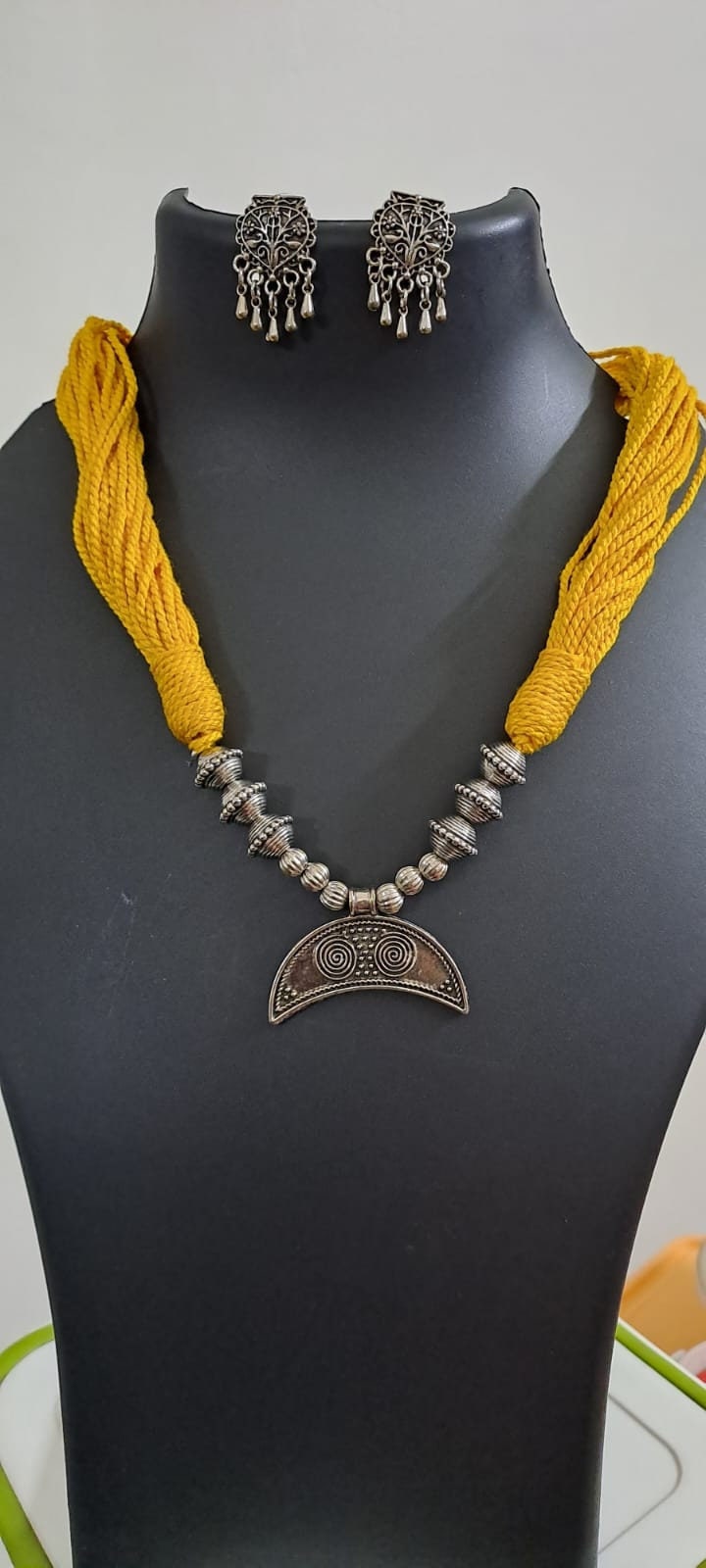 Yellow thread necklace with oxidised silver dokra pendant