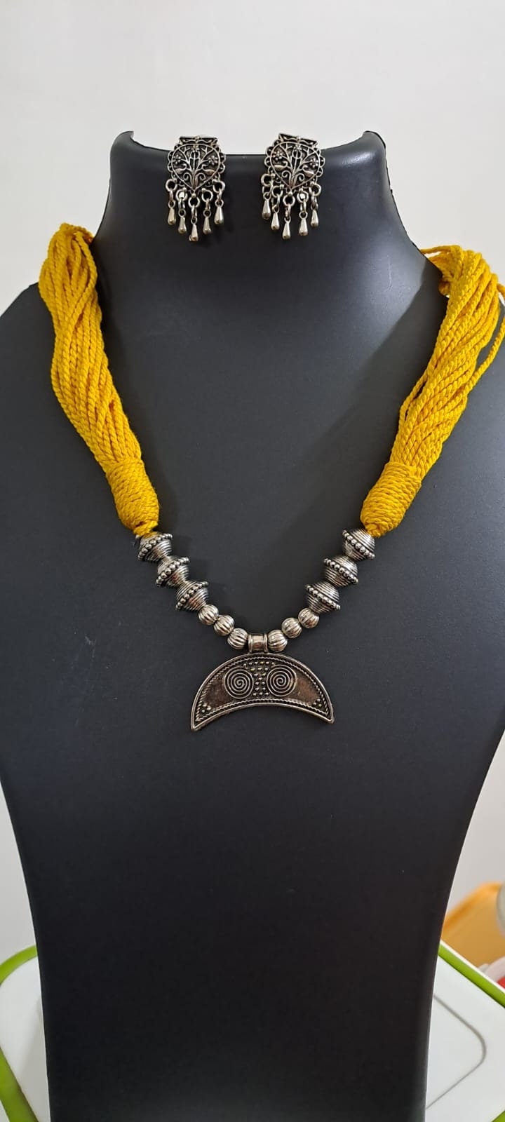 Yellow thread necklace with oxidised silver dokra pendant