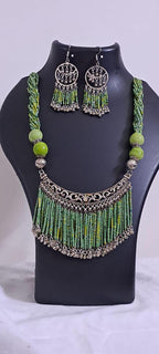Exclusive necklace with silver oxidised big oval pendant with seed beads fringes and matching earrings.